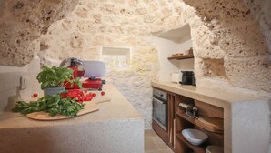 Uma cozinha com um arco de pedra, uma tábua de corte com legumes e uma máquina de café.