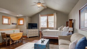 Un dormitorio acogedor con cama, cómoda, televisor y ventilador de techo.
