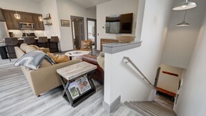 Un salon moderne avec un canapé, une table basse et un téléviseur fixé au mur.