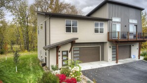 Une maison à deux étages avec un garage, un balcon et une pelouse bien entretenue.