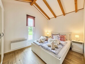 A bedroom with a bed, bedside tables, a window, and a radiator.