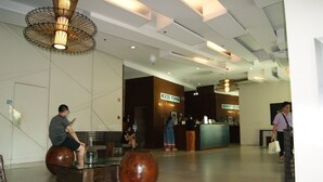 A lobby with a reception desk, seating areas, and a large vase. - The Beacon Makati by mvmtransient (Makati)
