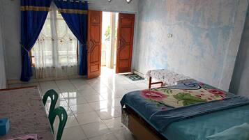 A bedroom with a bed, a table, chairs, and a window with curtains.