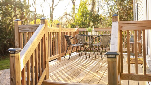 Une terrasse en bois avec une table et des chaises, entourée d’arbres.