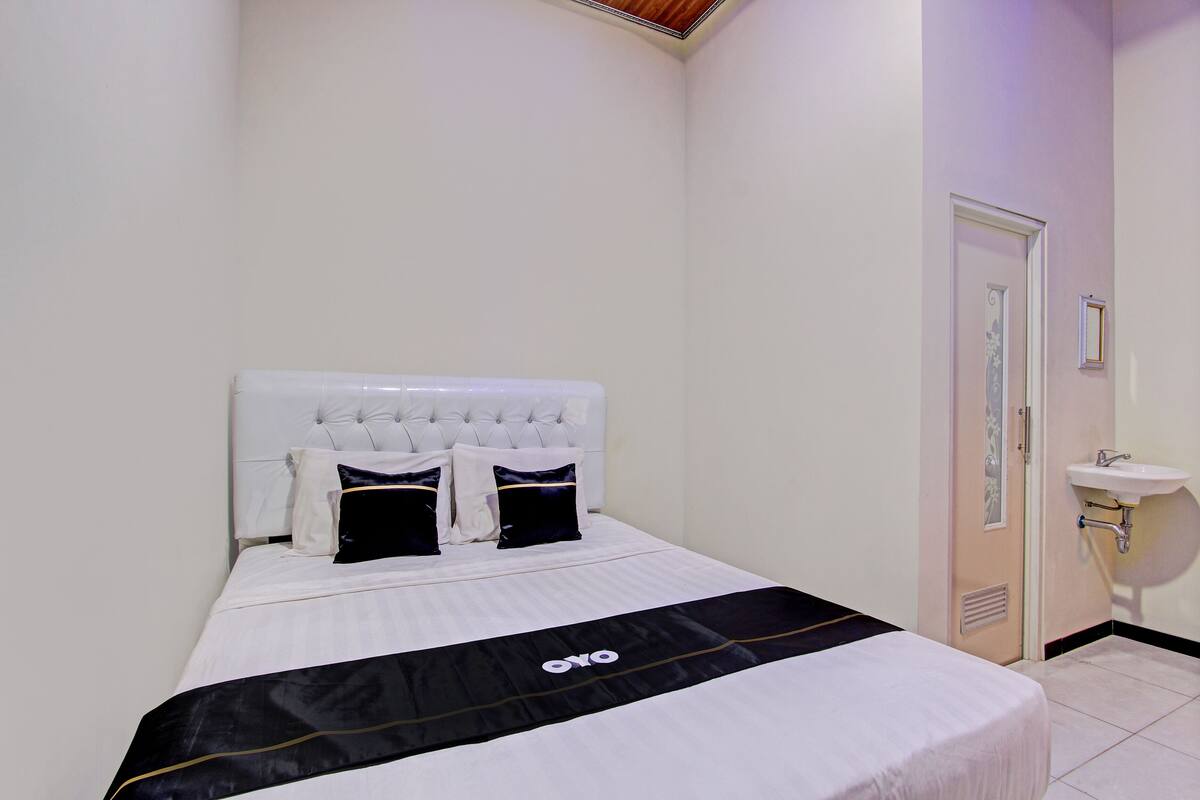 A neatly made bed with a black and white bedspread, a white headboard, and two black pillows.