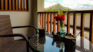 A balcony with wicker furniture, a glass table, and a vase with red flowers. - Santai Toraja (Rantepao)