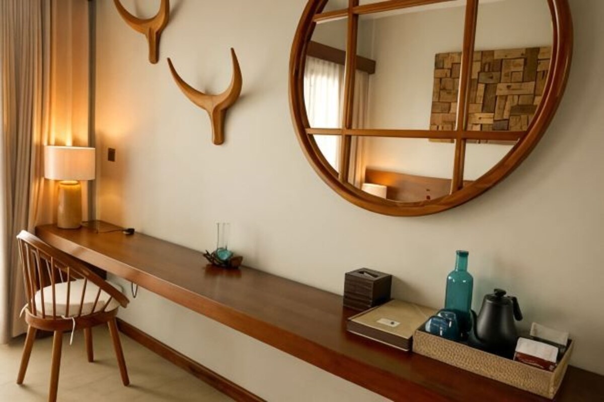 A room with a wooden bar, a round mirror, and a seating area with chairs.