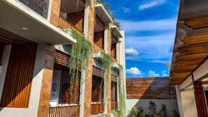 A multi-story building with balconies, wooden railings, and a clear blue sky. - Santai Toraja (Rantepao)