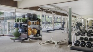 Une salle de sport équipée de matériel d’exercice, dotée d’un murmiroir et offrant une vue sur l’extérieur.