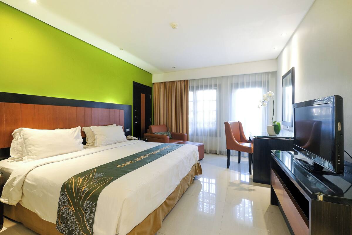 Una habitación de hotel con una cama grande, un televisor, un escritorio y una silla.