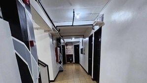 Un pasillo con suelo de baldosas, paredes blancas y puertas que dan a habitaciones.