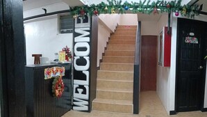 Un área de recepción con un cartel que dice 'WELCOME', una escalera y una puerta con un letrero en un idioma extranjero.