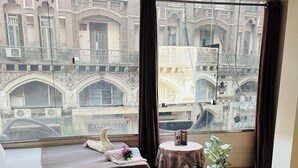 Ein Hotelzimmer mit großem Fenster, einem Bett, einem kleinen Tisch mit Pflanze und einer Schwan-Dekoration.