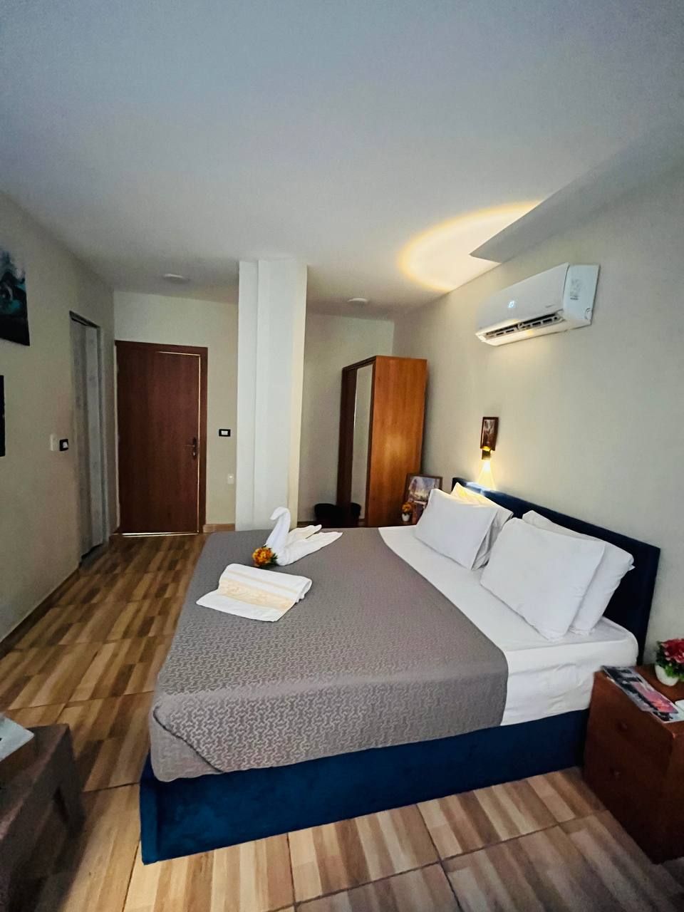 Una habitación de hotel con cama, mesita de noche y un equipo de aire acondicionado en la pared.