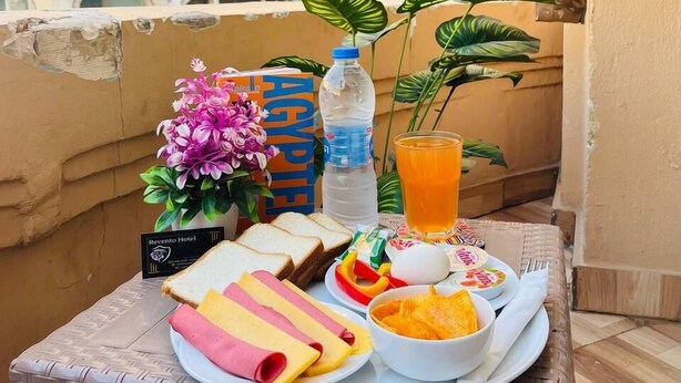 Ein Balkontisch mit Frühstücksangeboten, einer Wasserflasche und einem Glas Orangensaft.