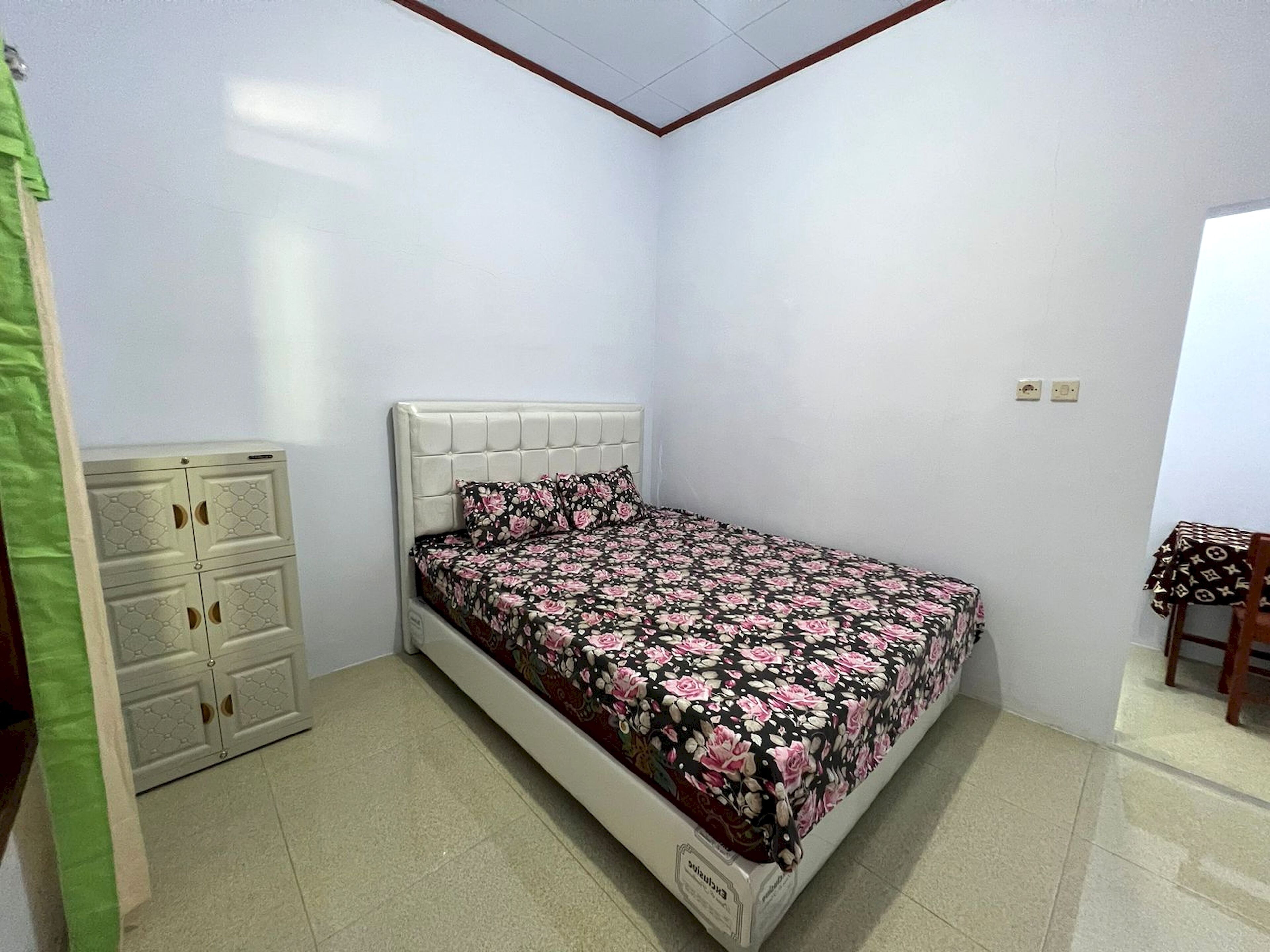 A small, neatly arranged bedroom with a single bed, a dresser, and a chair.