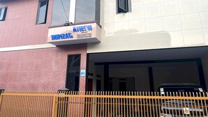 Um edifício com uma placa que indica "AMINAG" e "AMINAG" em letras azuis. Há uma pequena janela com moldura de metal e uma porta à direita da placa.