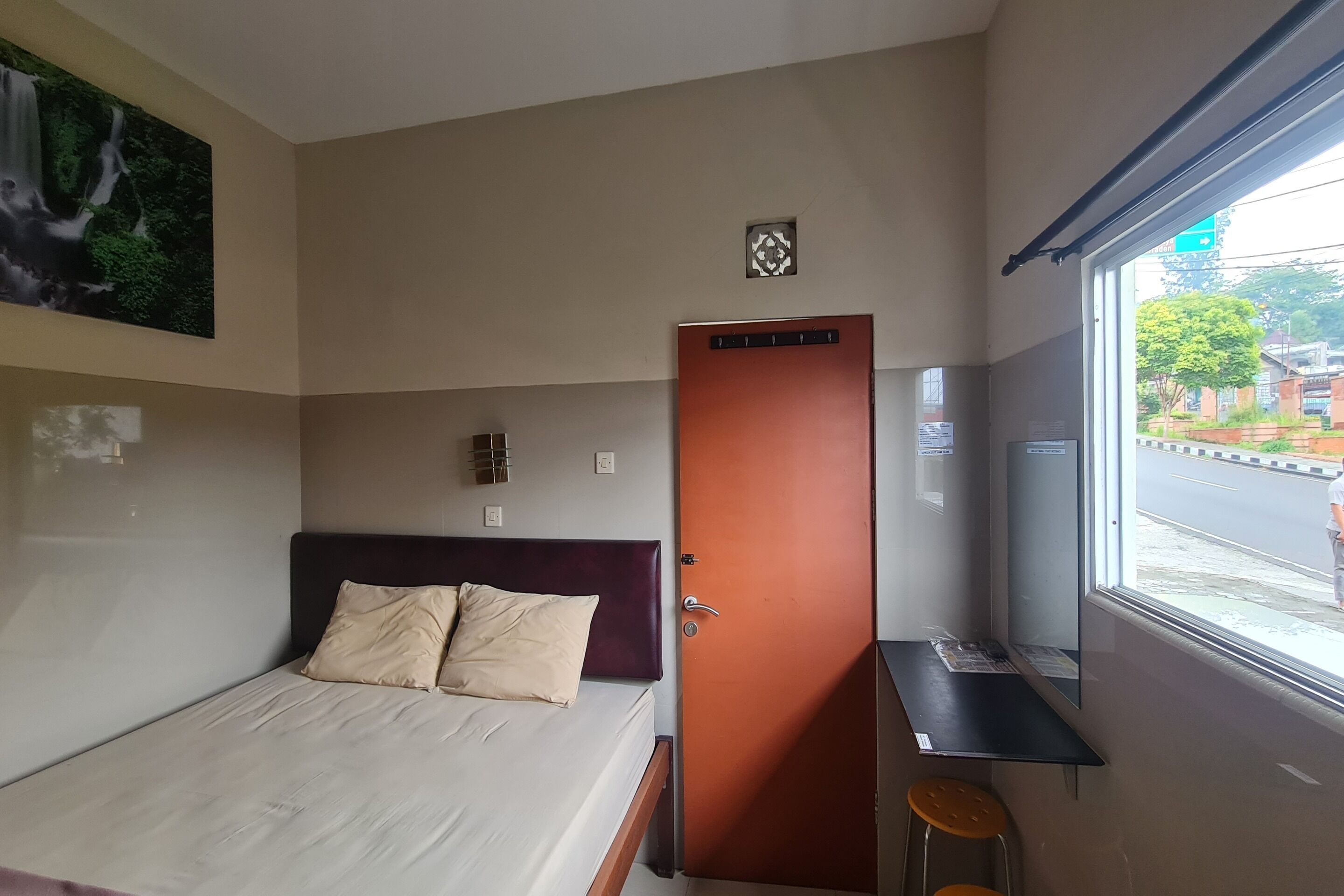 A hotel room with a bed, a door, a window, and a small table with stools.