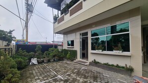 A modern building with a paved courtyard, potted plants, and a visible entrance.