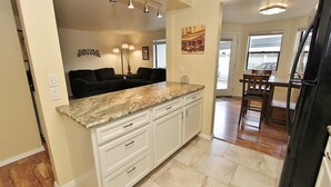 A kitchen with white cabinets, granite countertops, and a dining area with wooden chairs and a table. - SE Boise Condo • Pool • Parking • Hot Tub+ 2 Private Master Suites (Boise)