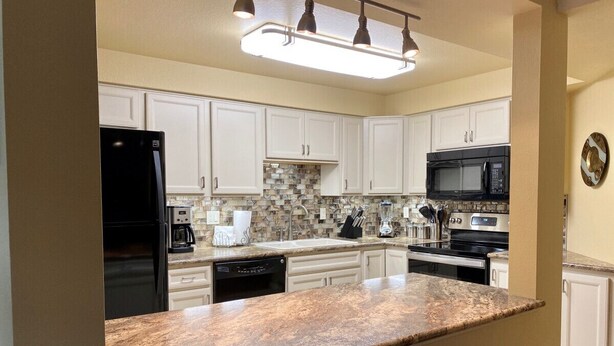 A modern kitchen with white cabinets, granite countertops, a black refrigerator, a microwave, and a dishwasher. - SE Boise Condo • Pool • Parking • Hot Tub+ 2 Private Master Suites (Boise)
