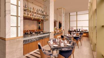 Un restaurant moderne doté de comptoirs en marbre, d’un bar avec des étagères remplies de bouteilles et d’une longue table à manger entourée de chaises.