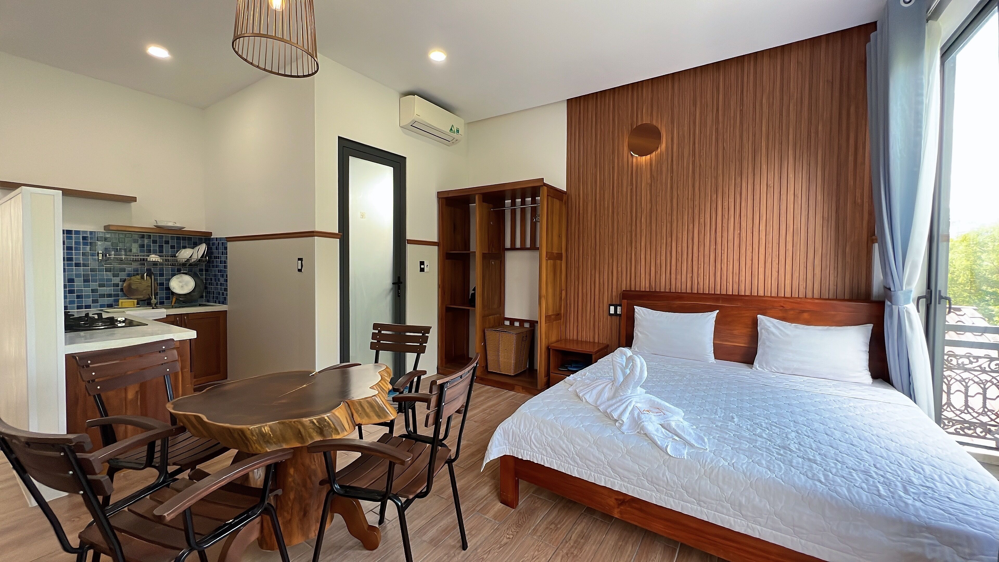 Une chambre avec un grand lit, une tête de lit en bois et une vue sur l’extérieur.