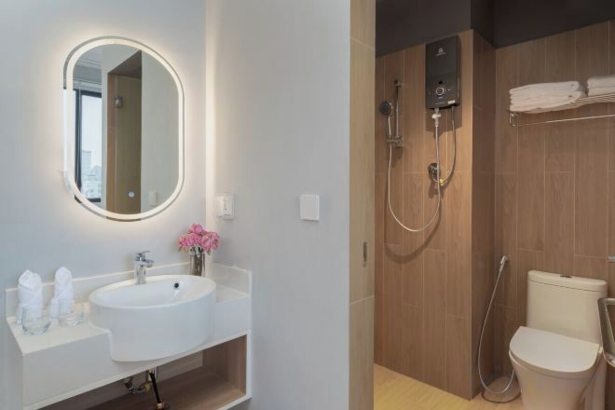 A modern bathroom with a round mirror, a sink, and a shower area.
