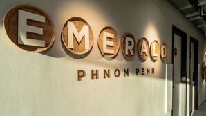 Una pared con el nombre "EMERALD PHNOM PENH" exhibido en letras grandes, indicando el nombre del hotel.