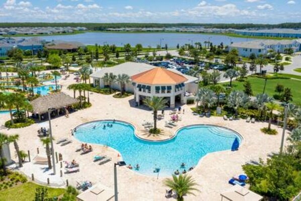 A resort with a large central pool, a gazebo, and a view of the surrounding landscape.