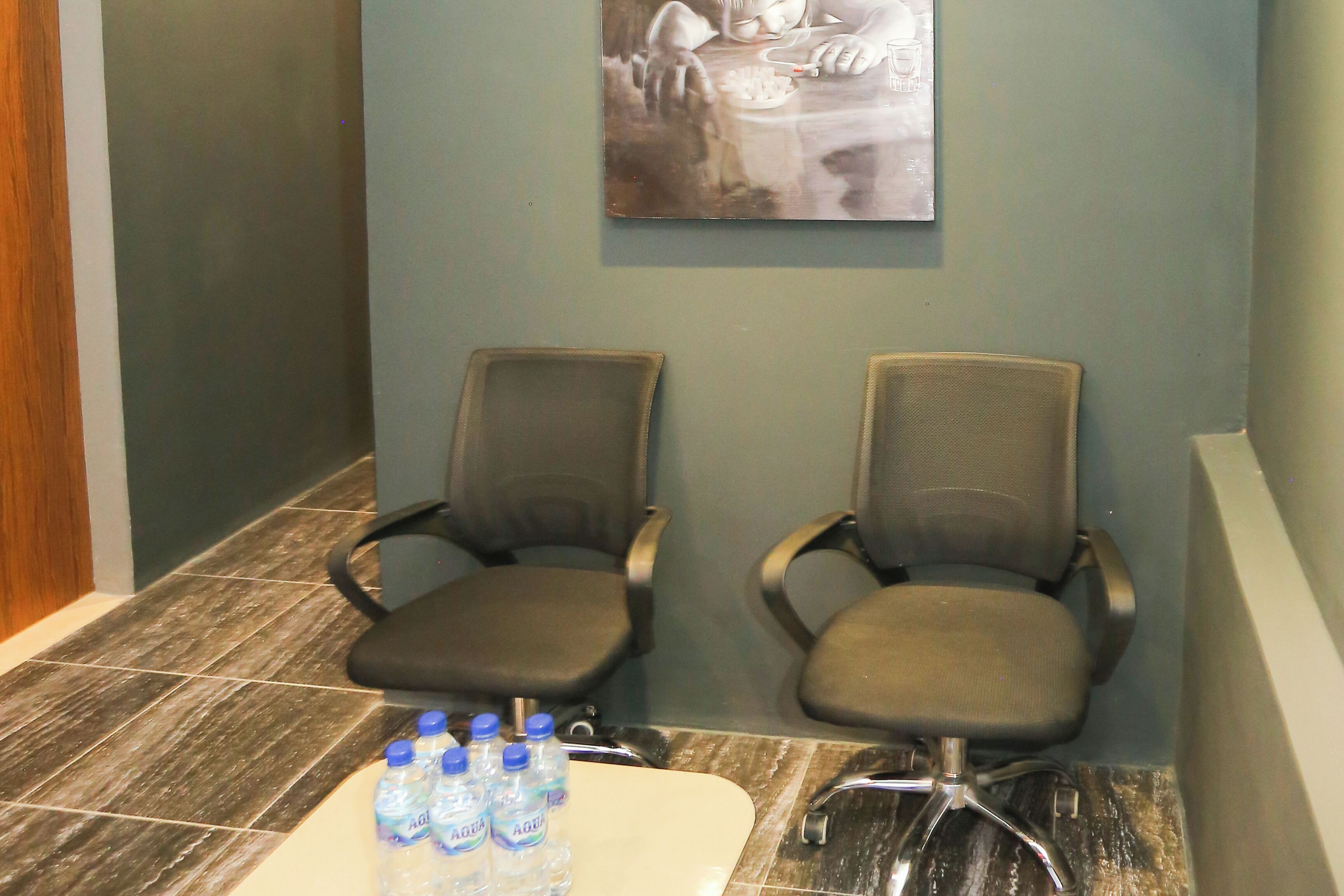 A waiting area with two chairs and a table with water bottles.