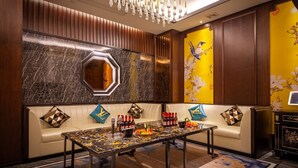 A modern lobby with a marble wall, a wooden panel wall, and a yellow floral wall. There is a seating area with a table set for a meal. - Ginlan jia hotel Hangzhou Xintiandi (Hangzhou)