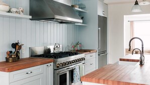 A modern kitchen with a stainless steel stove, wooden countertops, and a built-in oven. - Little Louis - A Princely Take on a County Getaway (Prince Edward)