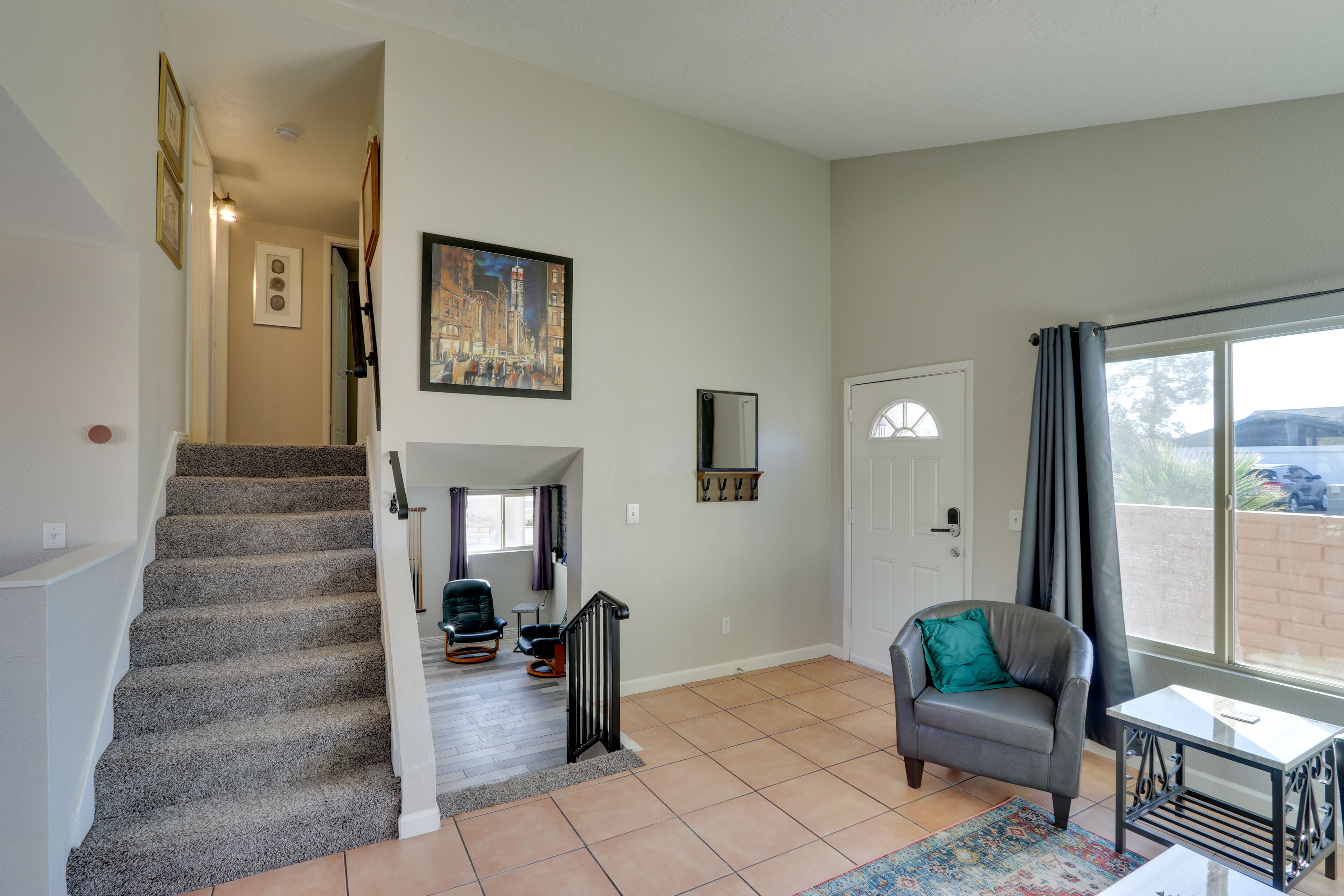 A spacious living area with a staircase, a sofa, a small table, and a large window.
