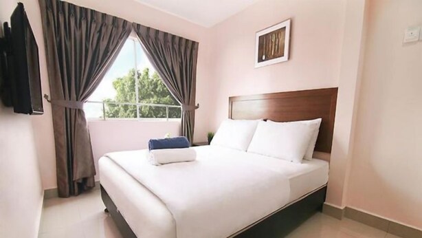 Una cama bien hecha en una habitación de hotel, con un cabecero, una ventana con cortinas y un cuadro en la pared.