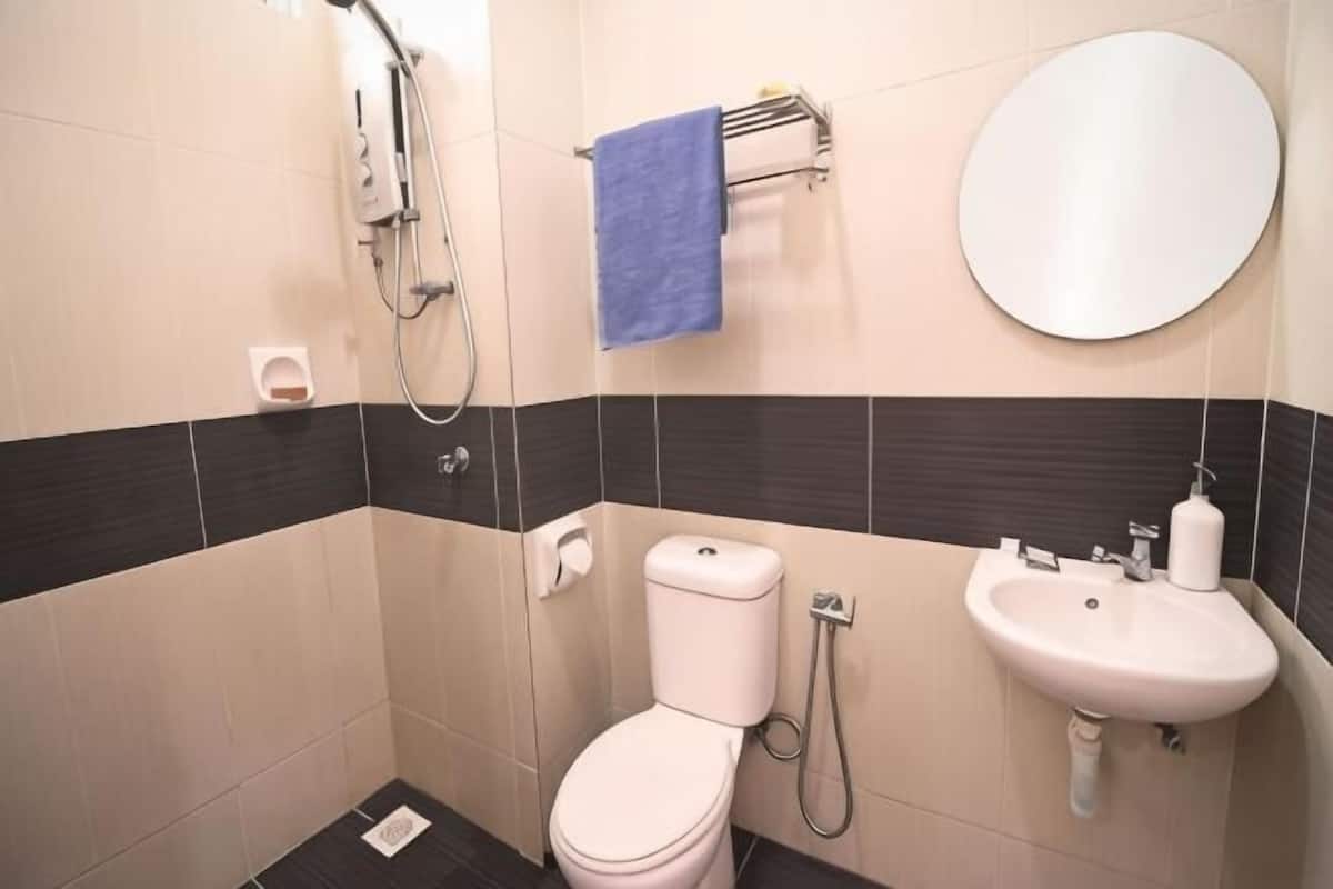 A bathroom with a toilet, sink, mirror, towel rack, and shower.