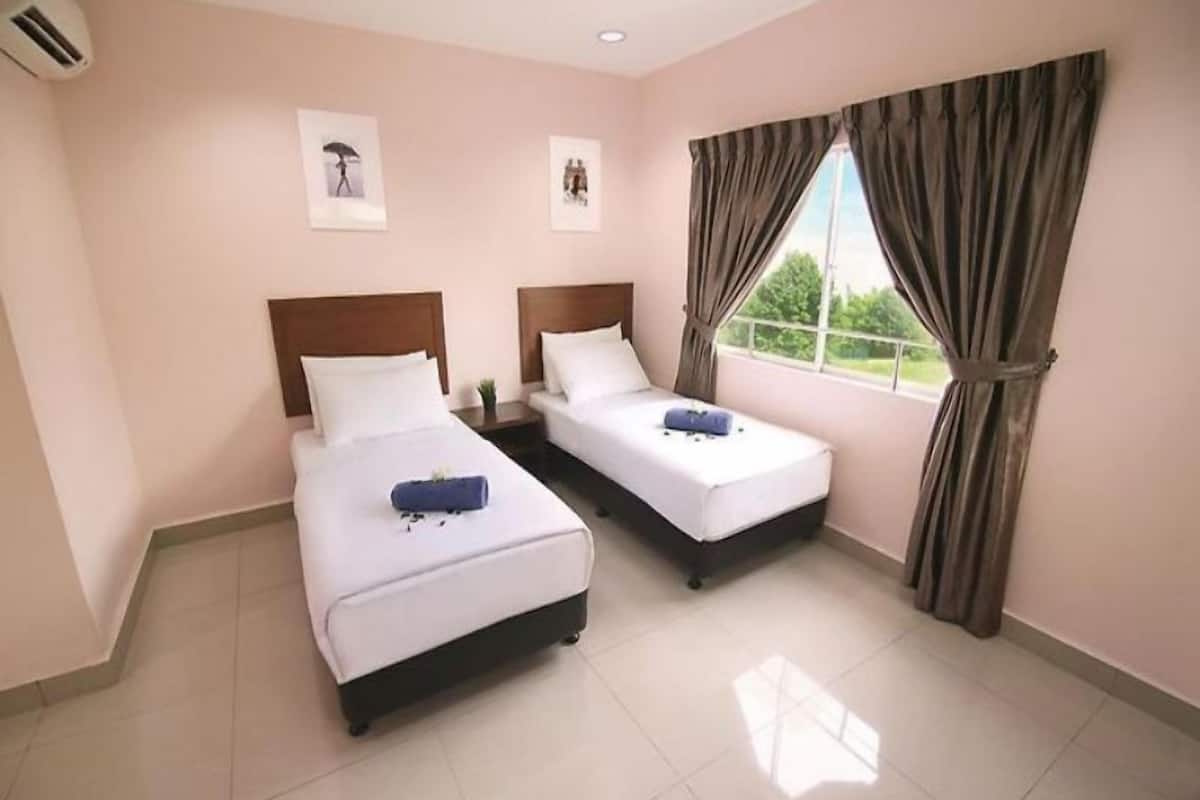 A hotel room with two single beds, a window with curtains, and artwork on the walls.