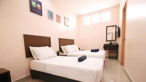 Una habitación de hotel con dos camas, un escritorio pequeño y un espejo.