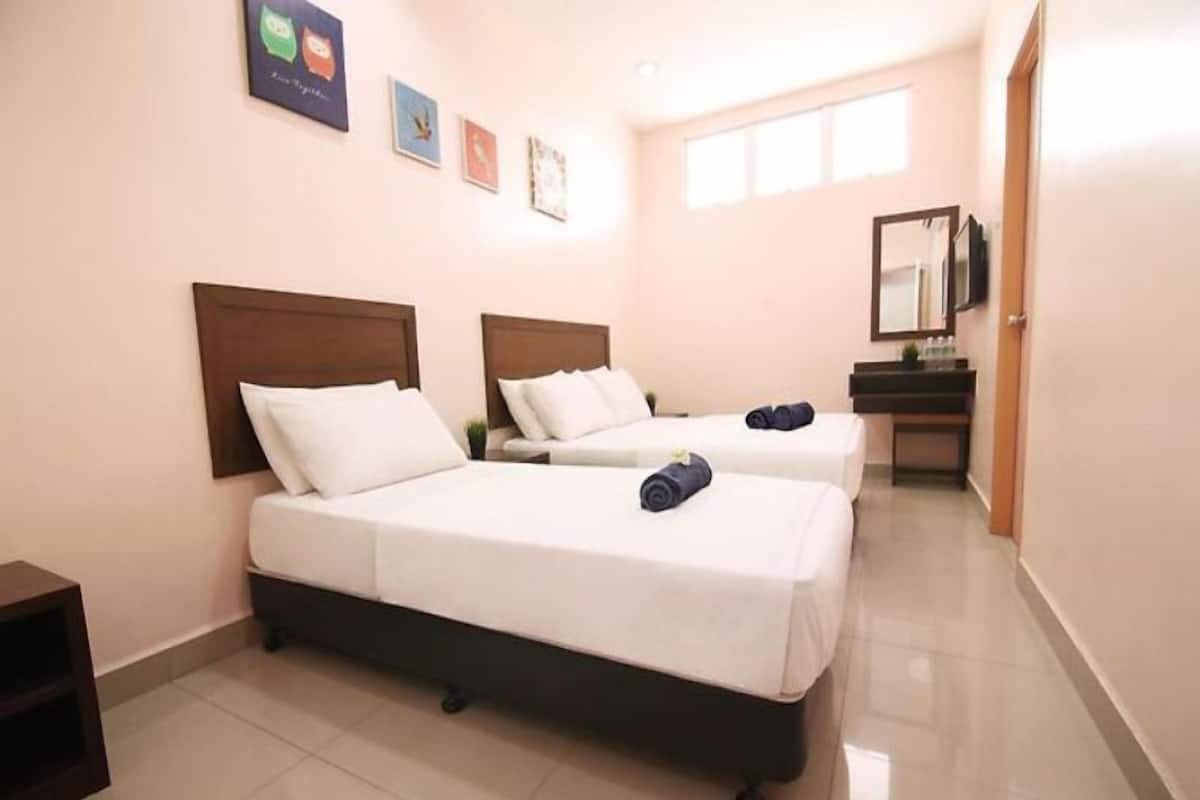 A hotel room with two beds, a small desk, and a mirror.