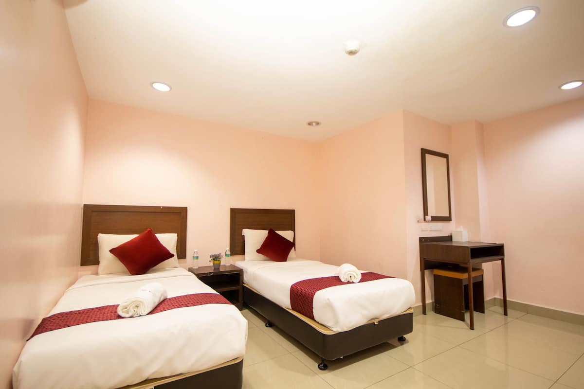A hotel room with two beds, a desk, and a mirror.