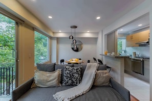 Una sala moderna con un sofá, una mesa de comedor y una zona de cocina.