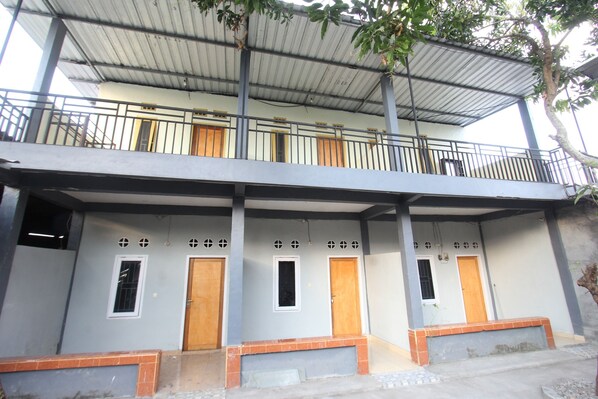 A two-story building with a balcony, multiple doors, and a covered entrance area. - OYO 93267 Barokah Rooms Syariah (Praya)
