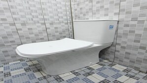 A bathroom with a toilet, tiled walls, and a patterned floor. - OYO 93267 Barokah Rooms Syariah (Praya)