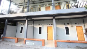 A two-story building with a balcony, multiple doors, and windows. - OYO 93267 Barokah Rooms Syariah (Praya)