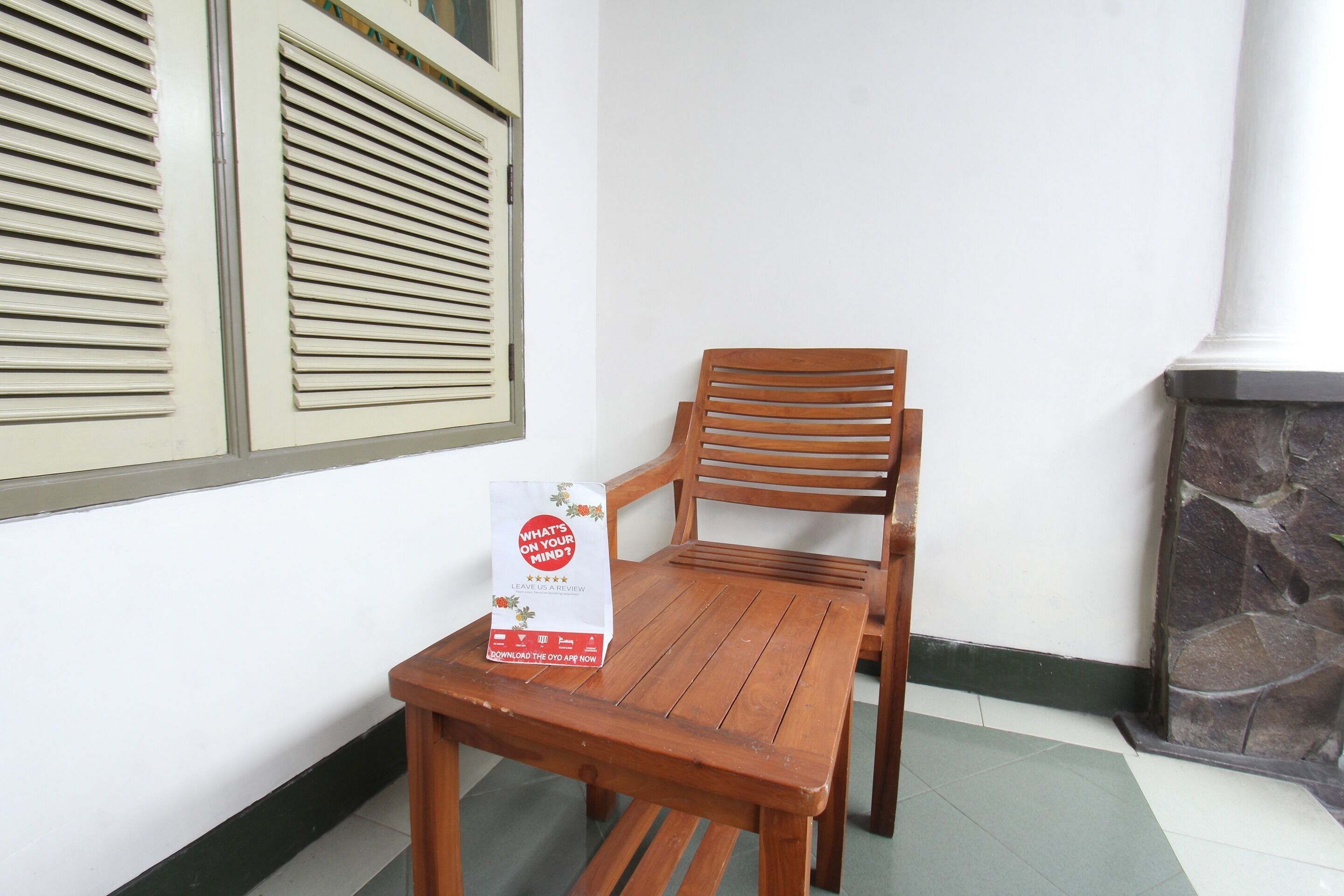 Um conjunto de mesa e cadeira de madeira num canto, com uma parede branca e uma lareira de pedra.