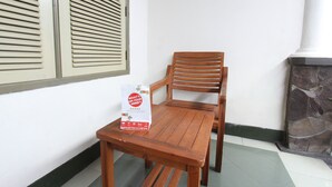 A wooden table and chair set in a corner with a white wall and a stone fireplace. - OYO 93267 Barokah Rooms Syariah (Praya)