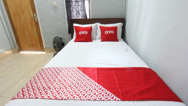 A bed with two red pillows labeled "OYO," a white bedspread, and a red and white patterned blanket. - OYO 93267 Barokah Rooms Syariah (Praya)
