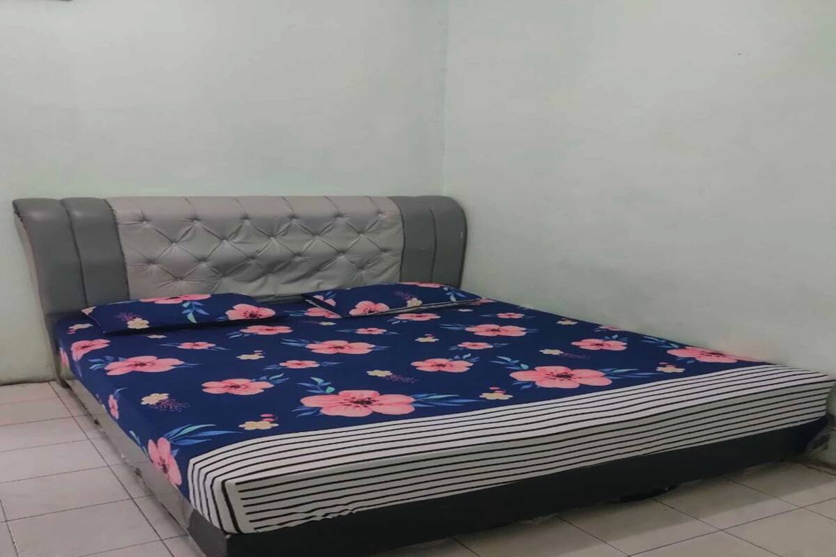 A bed with a tufted headboard, a floral bedspread, and a striped blanket.