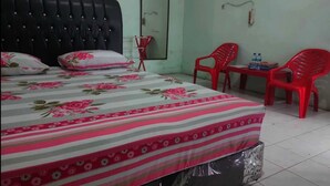 Une chambre à coucher avec un lit, une petite table, deux chaises, un miroir et une porte.
