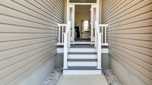 A narrow, covered stairway leading to a door with a white railing, flanked by siding walls. - Cape Charles Home: 4 Mi to Kiptopeke State Park! (Cape Charles)